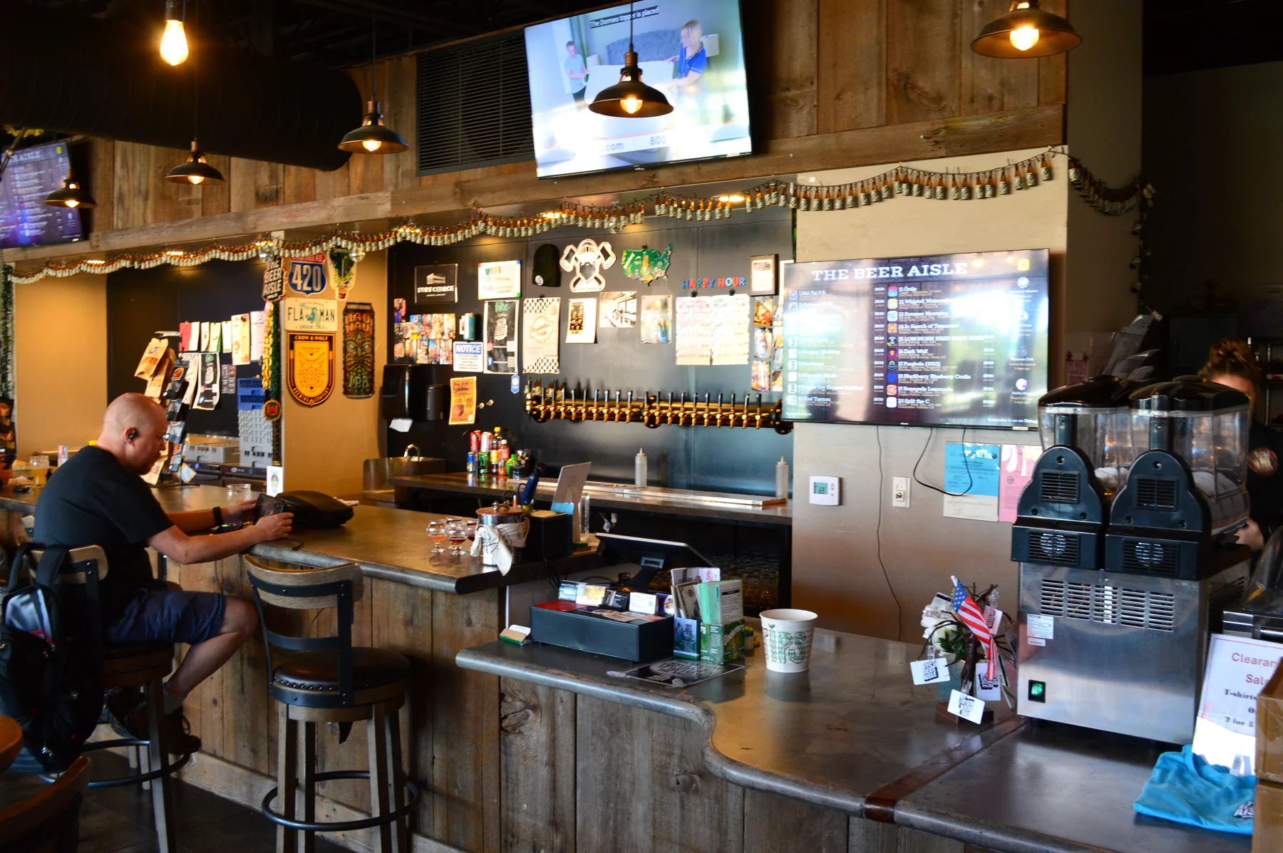 A guest enjoying the wood bar and relaxed atmosphere at The Beer Aisle.