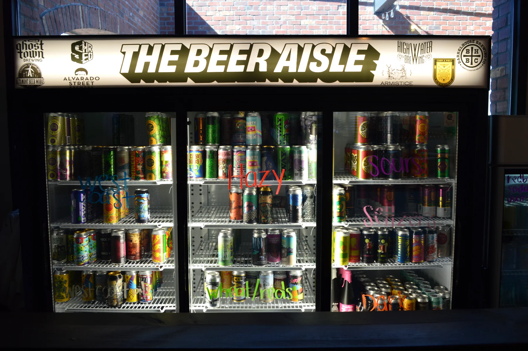 Refrigerated craft beer shelves beneath The Beer Aisle sign.