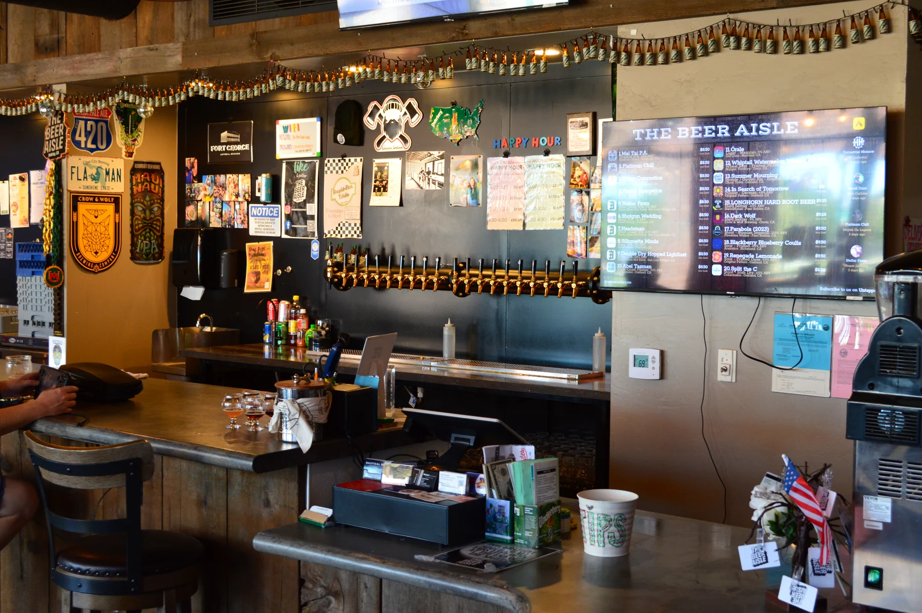 The Beer Aisle brass draft taps and digital beer menu behind the bar.